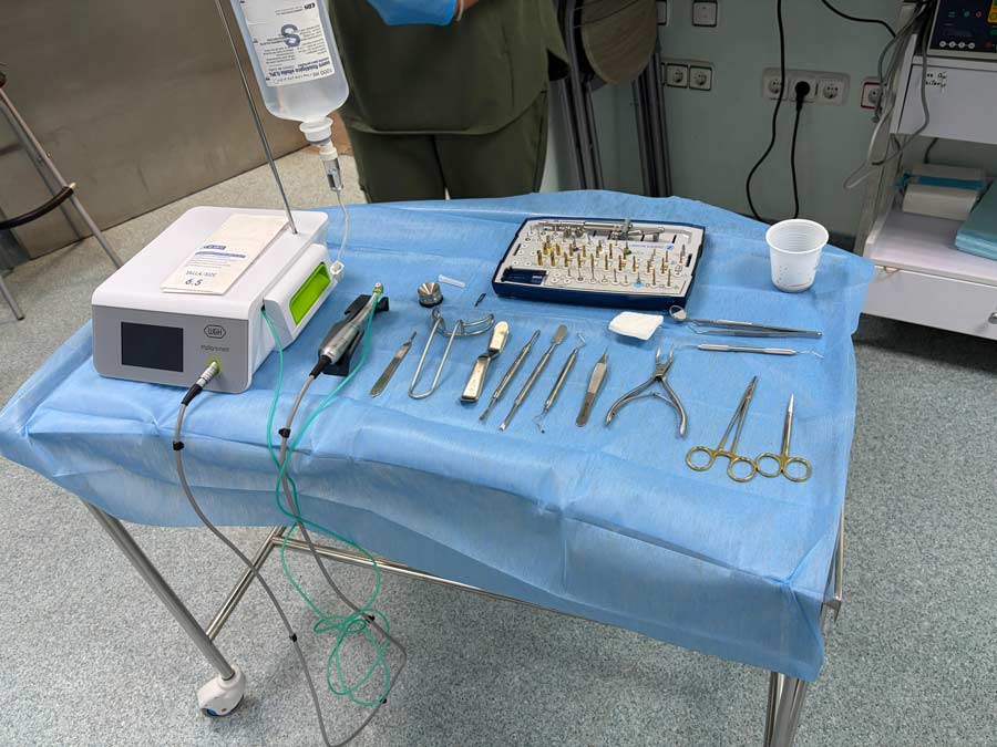 Instrumental quirúrgico esterilizado sobre mesa quirúrgica para cirugía dental, incluyendo motor de implantes, kit de fresas y herramientas de mano.